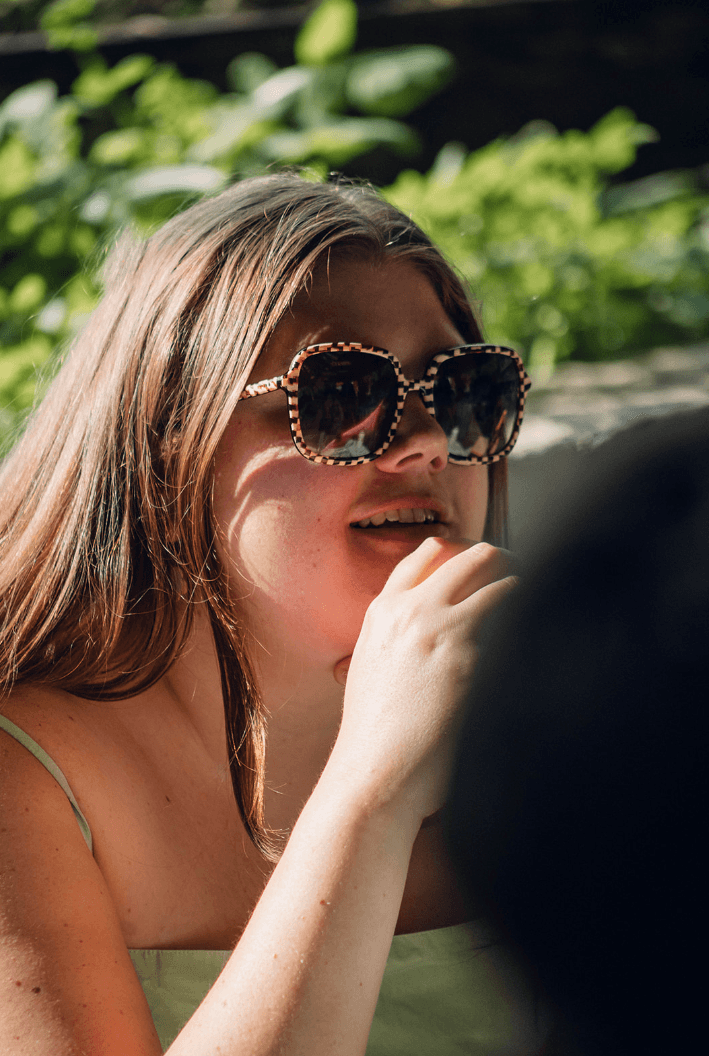 Photo of Alex Bunty with sunglasses and out of focus green foliage background