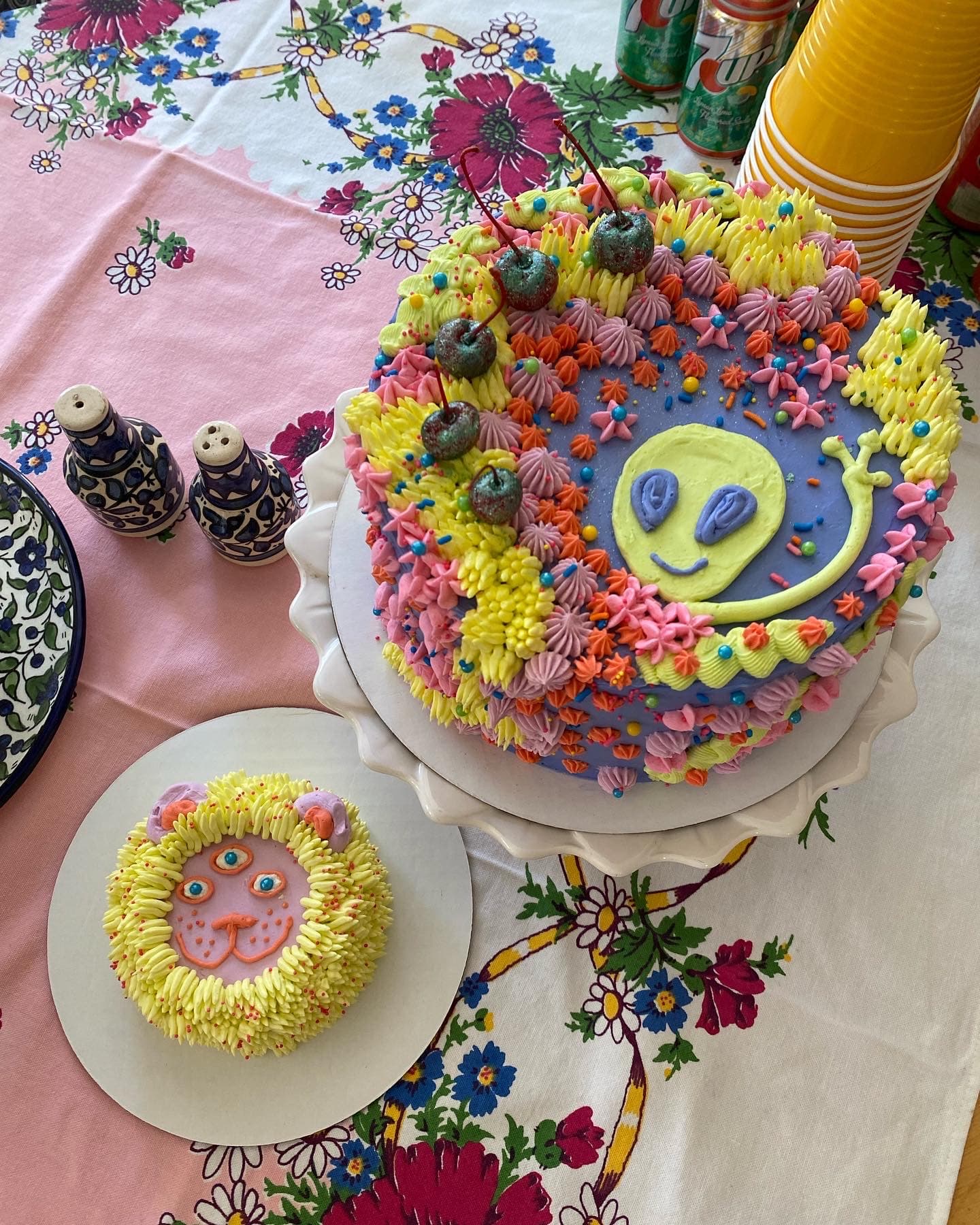 photo of a large cake with an alien on it and small cake that looks like a lion with three eyes