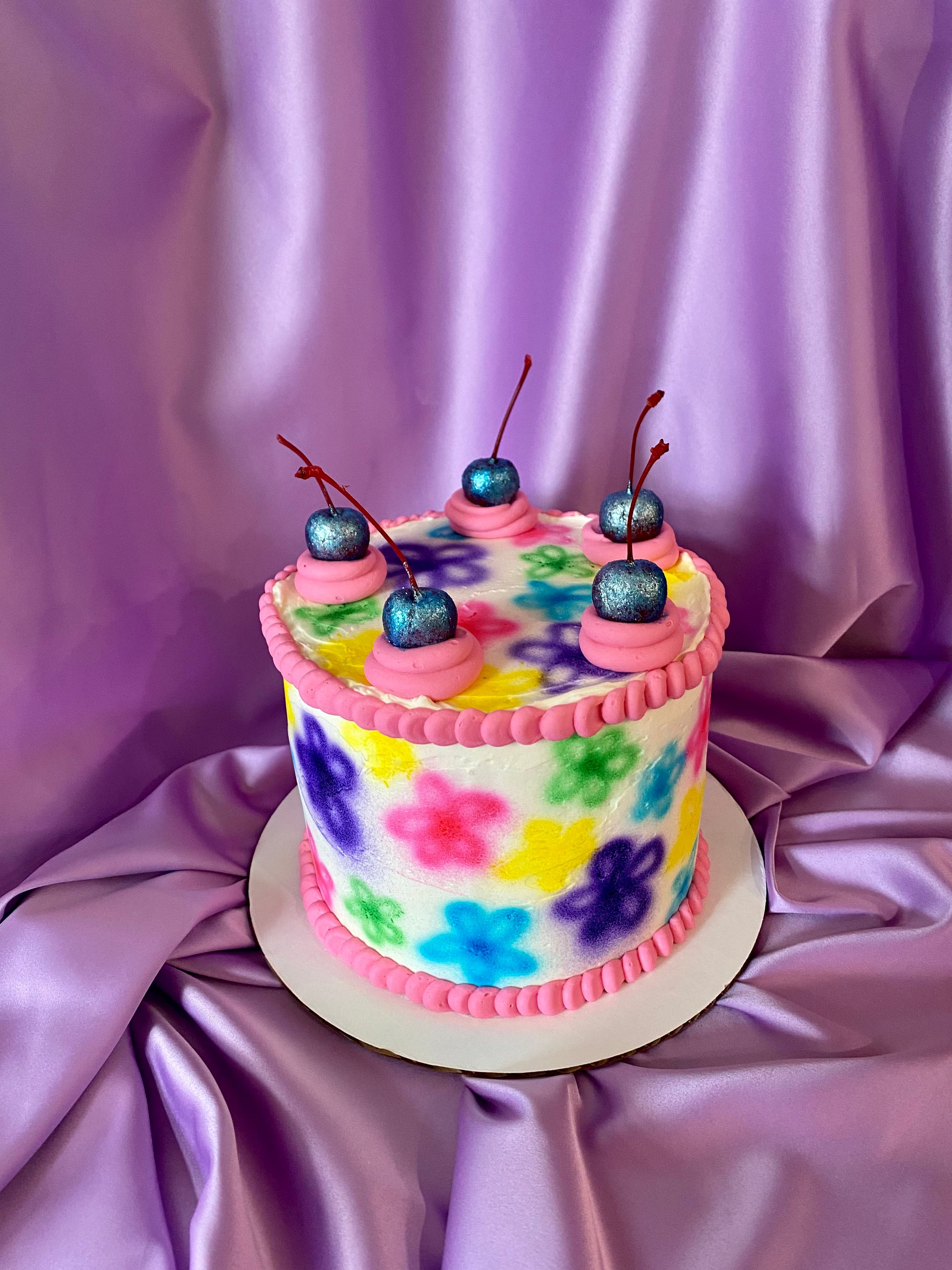 photo of a round cake with airbrushed daisies