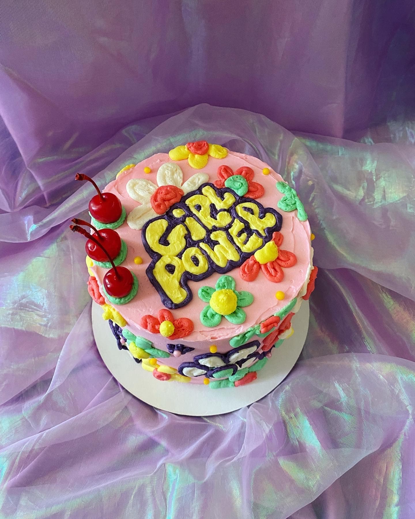 photo of a round cake with flowers that says girl power