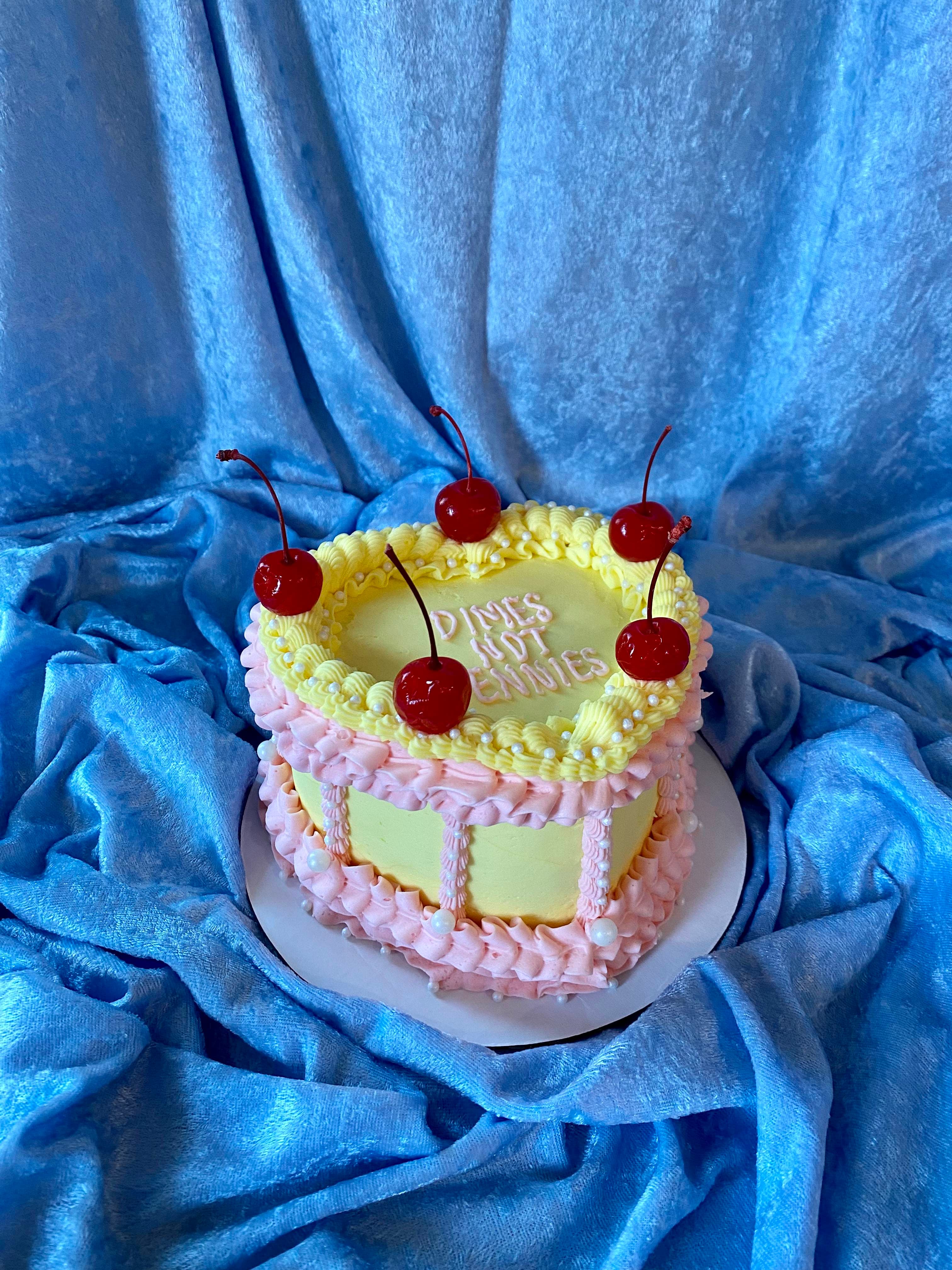 photo of a heart shaped cake with frilly decorations and cherries on top