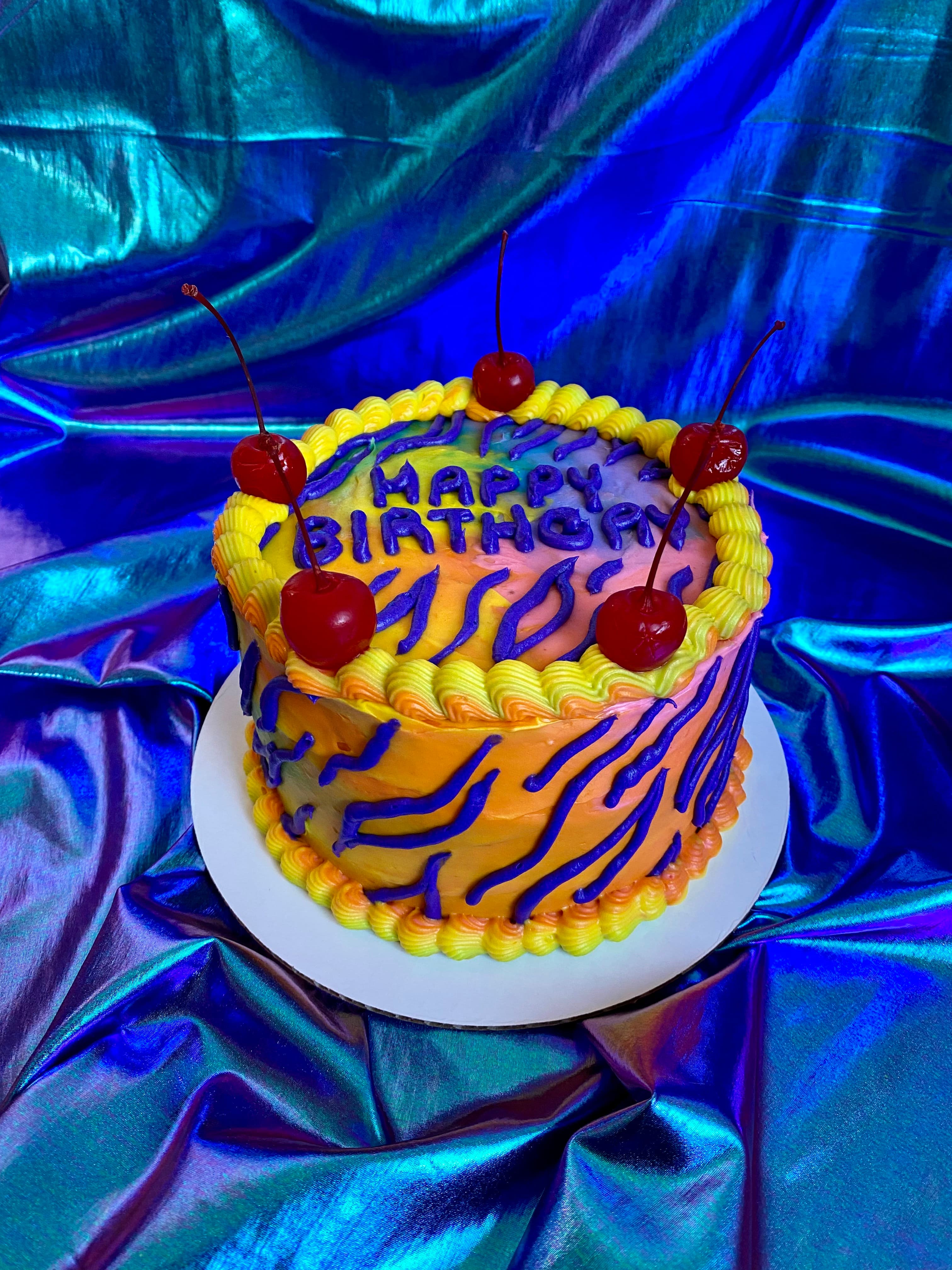 photo of a round rainbow colored cake with tiger stripes