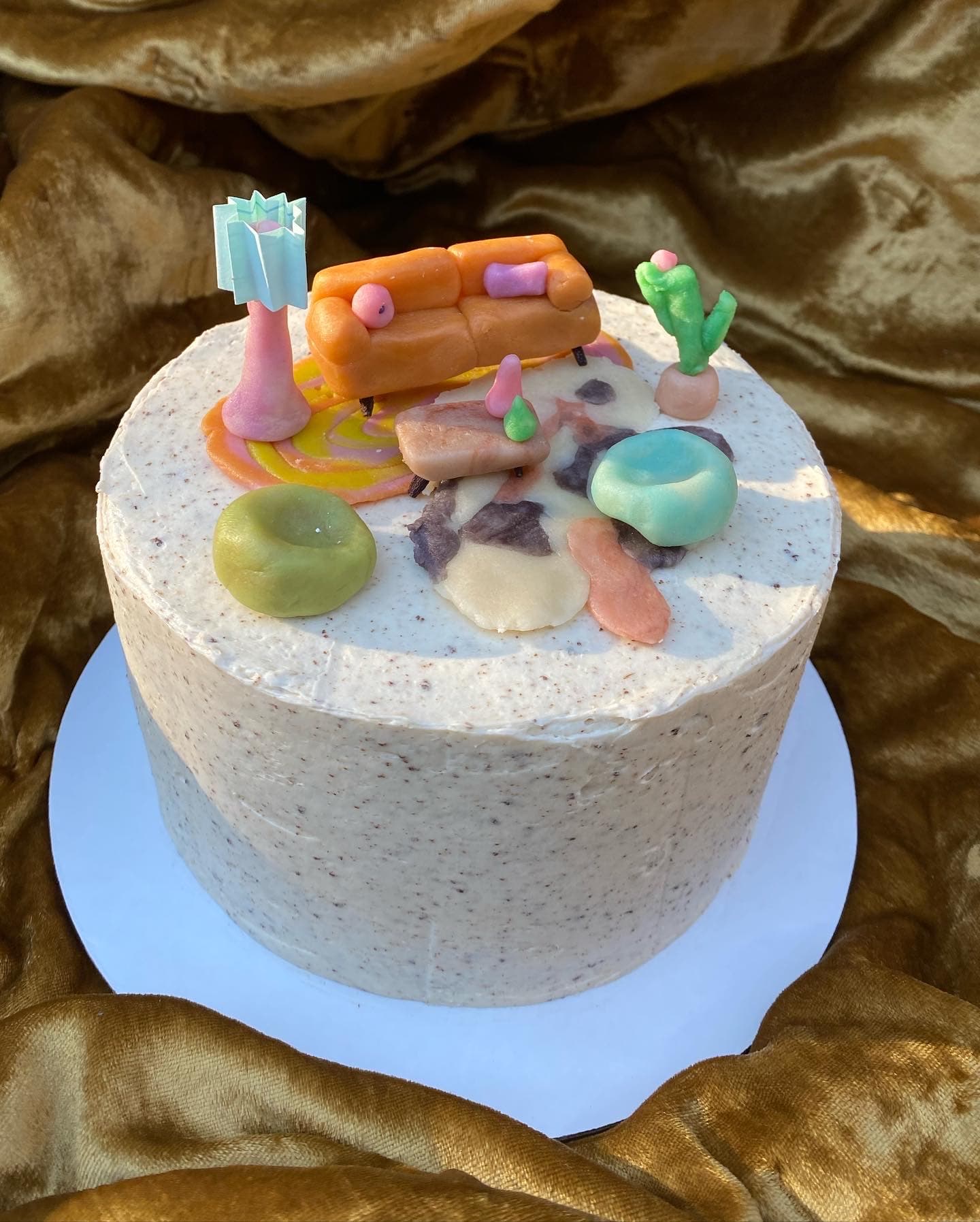 photo of a round cake with living room scene sculpted from marzipan