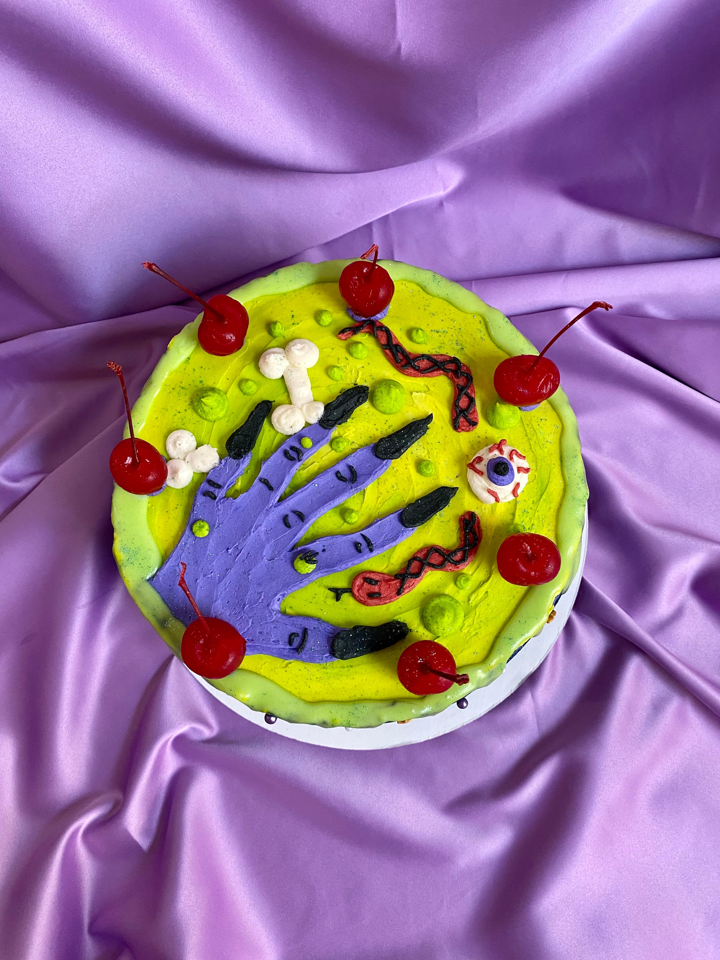 photo of a round cake with a purple witch hand, snake, and eyeball